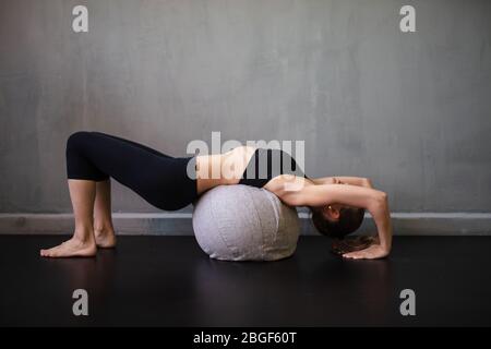 Eine kaukasische Frau Pilates Fitness trainieren schweizer Ball Übungen isoliert auf industriellen Hintergrund, moderne Wohnung Stockfoto