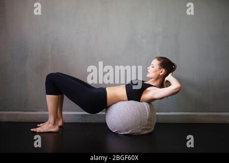 Athletische Frau, die ihre bauchmuskeln auf einem Ball in einem Industriehaus übt Stockfoto