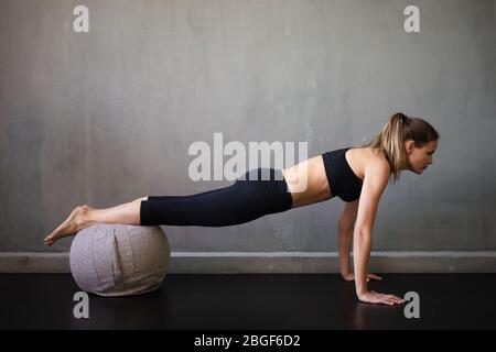 Eine kaukasische Frau Pilates Fitness trainieren schweizer Ball Übungen isoliert auf industriellen Hintergrund, moderne Wohnung Stockfoto