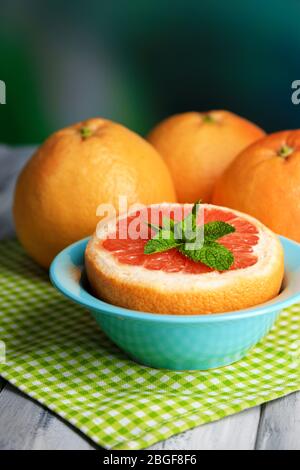 Reife Grapefruits in Schale auf farbigem Holztisch, auf hellem Hintergrund Stockfoto
