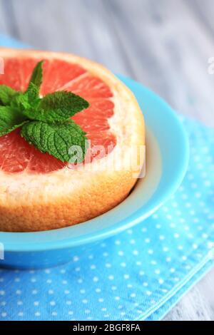 Reife Grapefruits in Schale auf farbigem Holzhintergrund Stockfoto