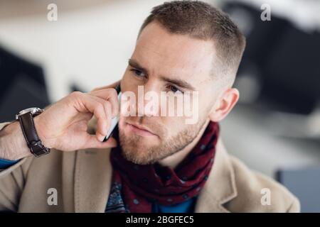 Geschäftsmann, der in der Wartelounge am Flughafen sitzt und auf den Flug wartet. Männlicher Manager in der Business Lounge des Flughafens, der im Wartebereich sitzt. Stockfoto