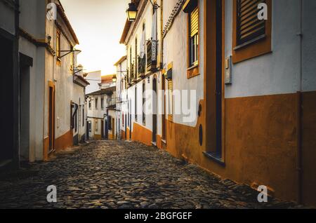 Sonnenuntergang in den Pfeilgassen von Evora, der Hauptstadt der Alentejo Region in Portugal, berühmt für seine traditionellen weißen und gelben Häuser Stockfoto