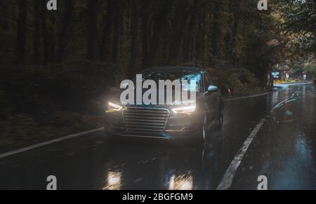 Autofahren auf der regnerischen Straße mit weißen Xenon-Lichtern bei Dunkelheit und gefährlichem Wetter Stockfoto