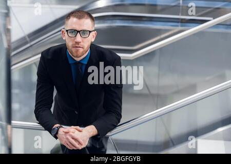 Eleganter junger erwachsener Mann auf der Treppe mit Tasche in der Hand. Er schaute auf die Kamera Stockfoto