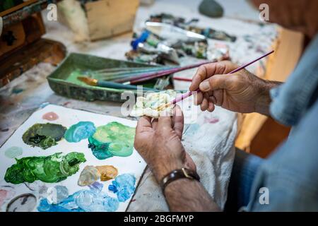 Ein Maler Senior Hände Reinigung einer Pinsel in einem Studio. Stockfoto