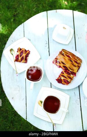 Couchtisch mit Teetassen und leckerer Torte im Garten Stockfoto