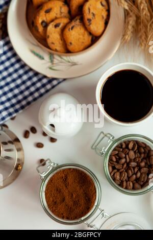 Weiße Tasse Kaffee und hausgemachte runde Plätzchen mit Schokoladenchips. Das Frühstück ist auf dem Tisch. Essen zu Hause. Stillleben. Kaffee und Kaffeebohnen. Ein Stockfoto