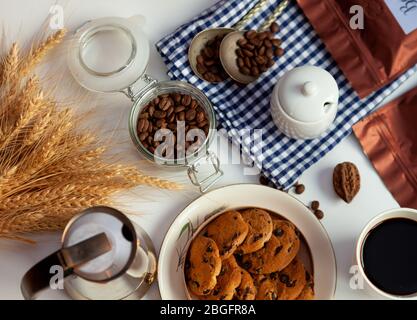 Weiße Tasse Kaffee und hausgemachte runde Plätzchen mit Schokoladenchips. Das Frühstück ist auf dem Tisch. Essen zu Hause. Stillleben. Kaffee und Kaffeebohnen. Ein Stockfoto