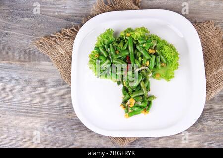 Salat mit grünen Bohnen, Schinken und Mais auf Platte, auf Farbe Holz- Hintergrund Stockfoto