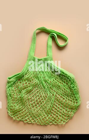 Leere Öko Einkaufstasche aus grünem Mesh auf beige. Konzept ohne Verschwendung. Blick von oben. Umweltfreundlich. Vertikales Format. Stockfoto