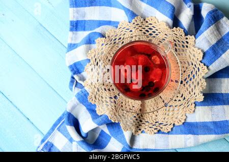 Fruchtroter Tee mit Waldbeeren in Glasbecher, auf Holzhintergrund Stockfoto