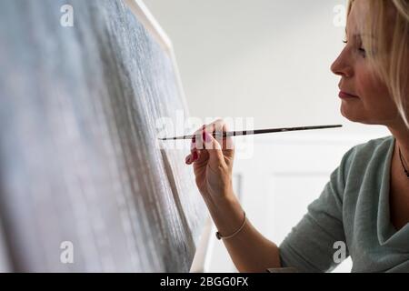 Eine Dame malt auf eine Leinwand. Stockfoto