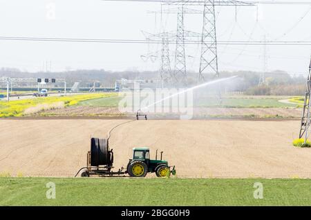 Traktor mit Bewässerungstechnik frisch gesät Feld in der Nähe von Elst, Niederlande Stockfoto