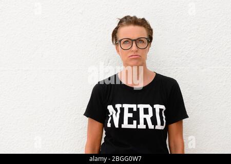Gelangweilte reife Nerd Frau mit großen Brillen und stehen vor weißem Hintergrund im Freien Stockfoto