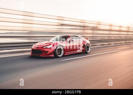 Rote elegante Sportwagen-Landschaft fahren über die Brücke Stockfoto