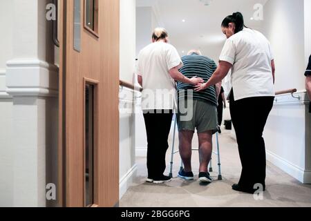 Mitarbeiter helfen einem Mann, der einen zimmer-Rahmen in einem Pflegeshaus in Redcar, Großbritannien, verwendet. 2/2/2018. Foto: Stuart Bolton. Stockfoto