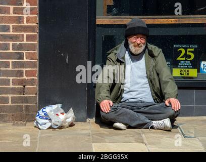 Windsor, Berkshire, Großbritannien. April 2020. Ein rauer Schläfer sitzt in Peascod Street, Windsor in der Morgensonne während der Coronavirus Pandemie. Kredit: Maureen McLean/Alamy Stockfoto