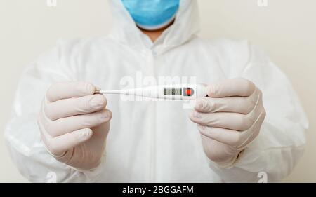 Arzt verwenden Thermometer zeigen Körpertemperatur überprüfen 39.0. Covid-19, Coronavirus Symptome. Arzt trägt schützende chirurgische Maske, biologische Gefahr Stockfoto