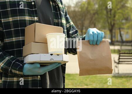 Kurier in medizinischen Handschuhen liefert Essen zum Mitnehmen Stockfoto