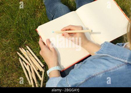 Mädchen zeichnet im Freien sitzen auf grünem Gras. Kreativitätskonzept Stockfoto