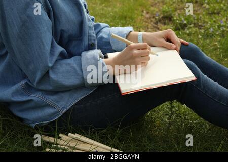 Mädchen zeichnet im Freien sitzen auf grünem Gras. Kreativitätskonzept Stockfoto