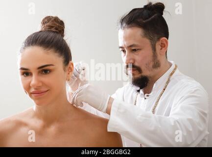 Asiatische Akupunktur tut Akupunktur zurück, um Frauen Schulterschmerzen zu lindern. Traditionelle chinesische Medizin. Stockfoto