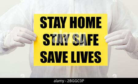 Stay Home Stay Safe Save Lives Text auf gelbem Warnschild in den Händen von Ärzten. Coronavirus, Covid-19 Selbstquarantäne-Isolierung. Medizin, Gesundheitswesen Stockfoto