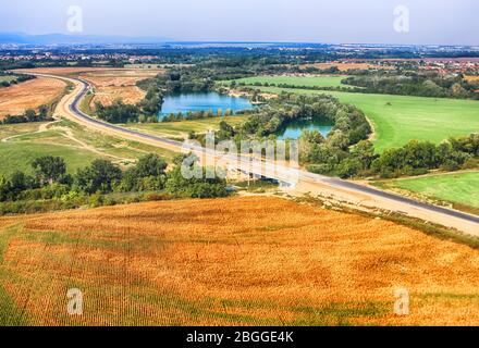 Blick auf landwirtschaftliche Felder, Seen und Straße im Sommer, Slowakei. Luftaufnahme. Dron View Stockfoto