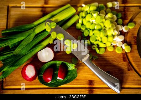 Gehackte grüne Knoblauchsprossen auf Schneidebrett und Messer Stockfoto