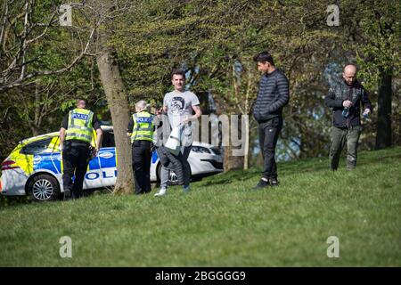 Glasgow, Großbritannien. April 2020. Im Bild: Eine Polizeiwache spricht mit Menschen, die auf dem Gras liegen und sich sonnen und sie weiterbewegen, während sie die Coronavirus-Gesetzgebung von einer Stunde Bewegung pro Tag durchsetzen. Szenen aus dem Kelvingrove Park in Glasgow während der Sperrung des Coronavirus (COVID-19). Quelle: Colin Fisher/Alamy Live News Stockfoto