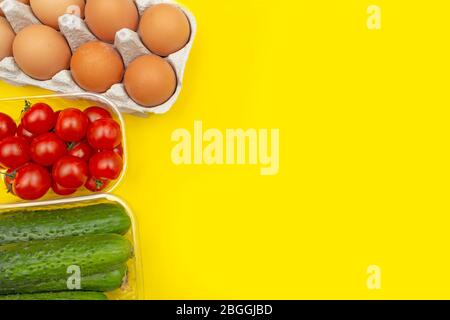 Frische Zutaten zum Kochen. Gemüse Tomaten, Gurken und rohe Eier auf gelbem Hintergrund. Kopierbereich. Stockfoto