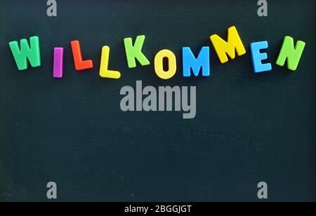 Tafel mit bunten Buchstaben in deutscher Sprache Willkommen übersetzen Welcome Stockfoto