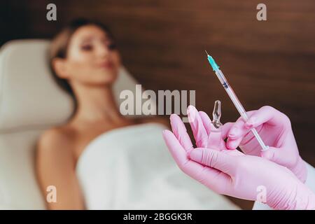 Kosmetikerin hält Spritze und Ampulle mit Flüssigkeit für die Injektion. Schönheitsspritzen Stockfoto