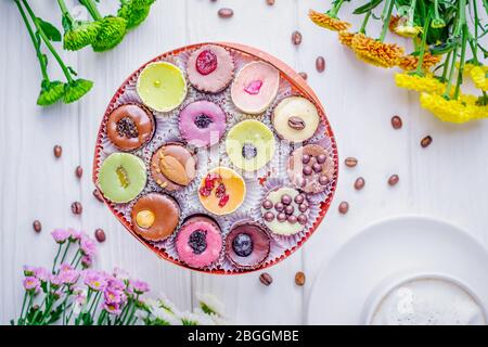 Verschiedene Luxus-Schokolade Bonbons in einer Geschenkbox und farbigen Chrysanthemen auf weißem Hintergrund. Draufsicht Stockfoto