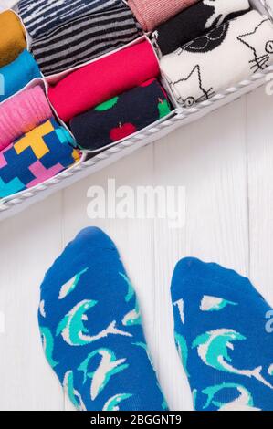 Box mit verschiedenen bunten Socken. Füße Selfie und ein Socken Organizer auf weißem Hintergrund. Draufsicht Stockfoto
