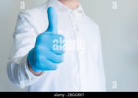 Mann in blauen medizinischen Handschuh zeigt Genehmigung Daumen nach oben Zeichen auf weißem Hintergrund mit Kopierraum für Text. Stockfoto
