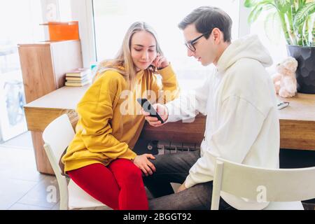 Der Typ und das Mädchen schauen auf das Smartphone und kommunizieren. Stockfoto