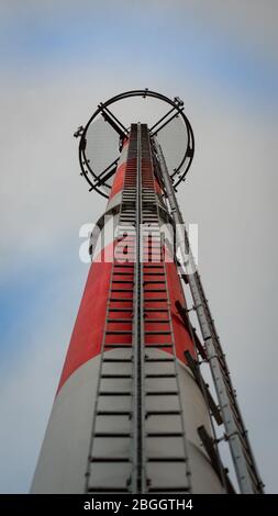 Hoher rot-weißer GSM-Kommunikationsturm mit Antennen oben; Ansicht von unten Stockfoto