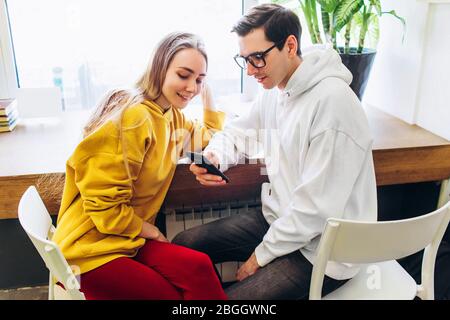 Der Typ und das Mädchen schauen auf das Smartphone und kommunizieren. Stockfoto
