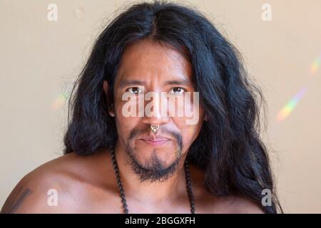 Porträt eines jungen hispanischen Mannes mit langen Haaren, der ein metallisches Septumpiercing an der Nase trägt Stockfoto