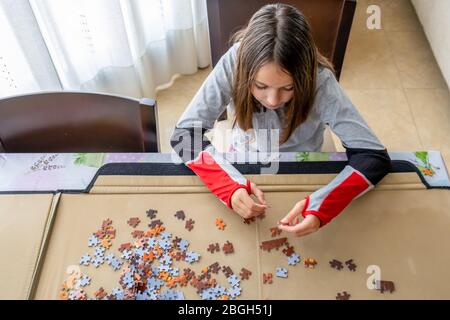 Hübsches kleines Mädchen im Sport Trainingsanzug tun Puzzle in ihrem Wohnzimmer. Unterhaltungskonzept Stockfoto