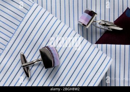 Gestreiftes Herren-Shirt in Weiß und Blau mit bunten Manschettenknöpfen. Kleiderordnung für Geschäftsreisende. Nahaufnahme. Selektiver Fokus. Stockfoto