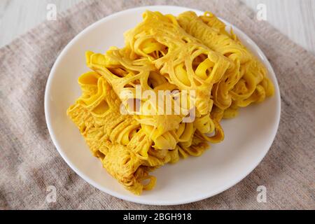 Hausgemachte Net Crepe Roti Jala auf einem weißen Teller auf einem weißen Holzhintergrund, niedrigen Winkel Blick. Nahaufnahme. Stockfoto