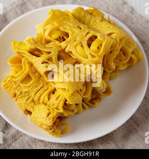 Hausgemachte Net Crepe Roti Jala auf einem weißen Teller auf einem weißen Holztisch, Seitenansicht. Nahaufnahme. Stockfoto