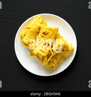 Hausgemachte Net Crepe Roti Jala auf einem weißen Teller auf schwarzem Hintergrund, Draufsicht. Flach liegend, überkopfstehend, von oben. Nahaufnahme. Stockfoto