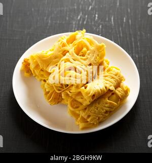 Hausgemachte Net Crepe Roti Jala auf einem weißen Teller auf schwarzem Hintergrund, Low-Winkel-Ansicht. Nahaufnahme. Stockfoto