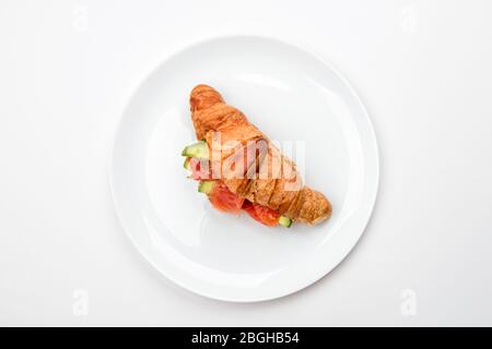 Sandwich mit Lachs und Avocado in einem Croissant auf einem weißen Teller. Stockfoto