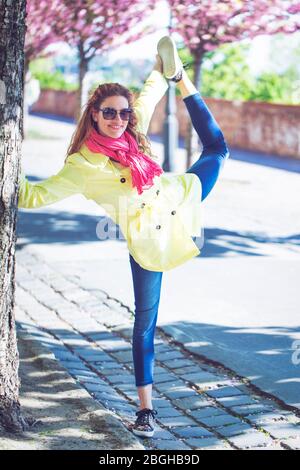 Junge Rotschopf Frau posiert wie Schwan im Park während Sakura Stockfoto