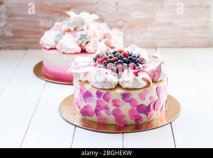 Weißer und rosa Birhday Kuchen mit Baiser und frischen Beeren, Himbeeren, Erdbeeren und Heidelbeeren. Weißer Holzhintergrund. Stockfoto